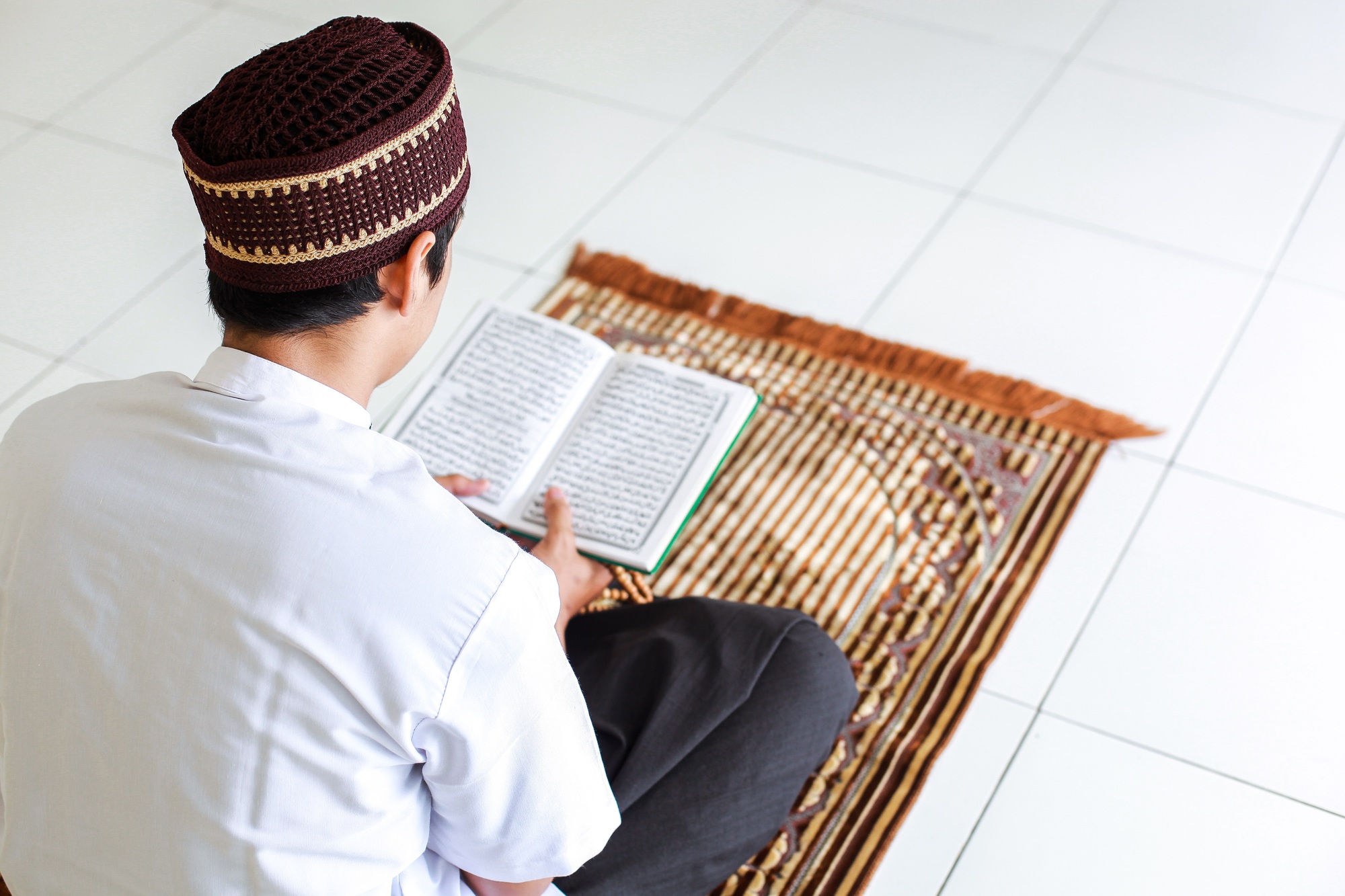 Muslim Man Reading Holy Quran on Prayer Mat